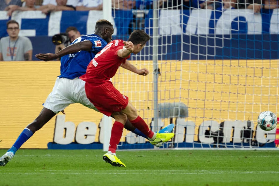 Schalkes Salif Sane (l) kann Bayerns Robert Lewandowski nicht davon abhalten, das 3:0 zu erzielen.