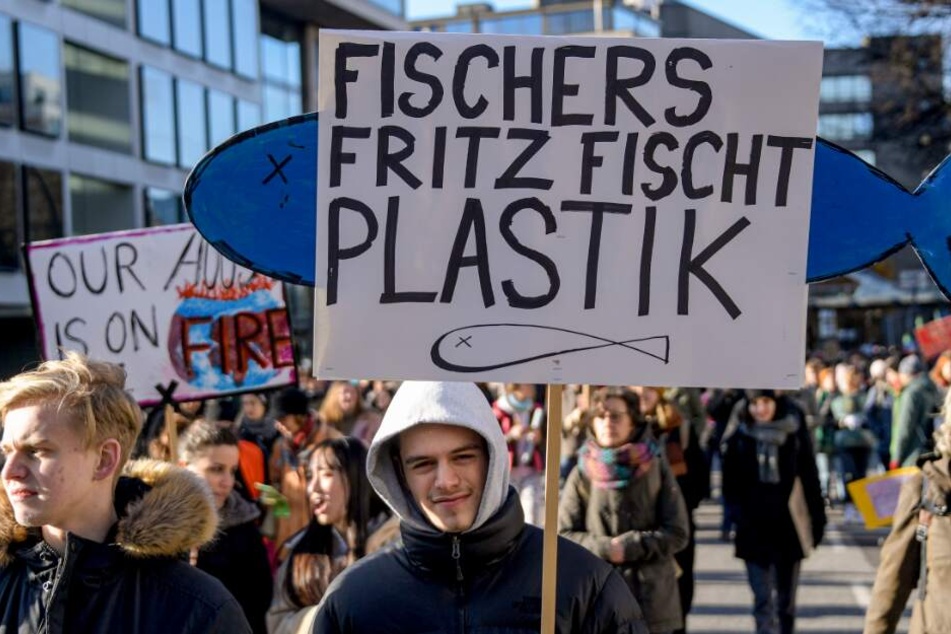 Ein Demonstrant hält ein Plakat in die Höhe.