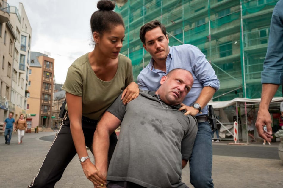 Ann-Christin "AC" (gespielt von Jane Chirwa) und Kilian (Francois Goeske, r.) nehmen den Ex-Boxer Marcel John (Urs Rechn) auf Halles Straßen fest.
