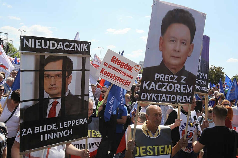 "Nieder mit dem Diktator Kaczynski" (re.) und dem "Verlierer" Ziobro (li.) steht auf Plakaten beim Protestmarsch "Wir sind und bleiben in Europa" in Warschau.