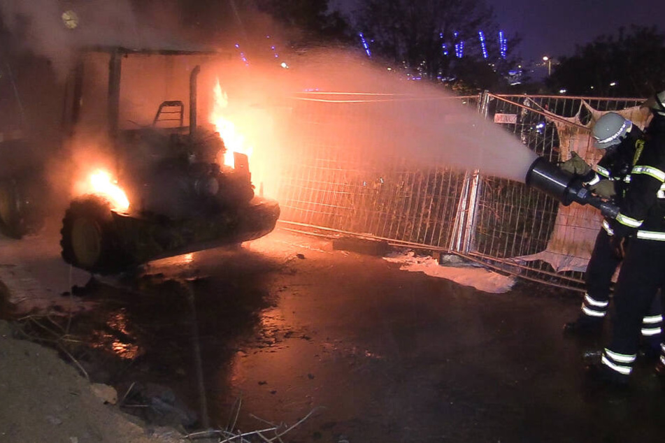 Feuerwehrmänner löschen den brennenden Radlader an den Landungsbrücken.