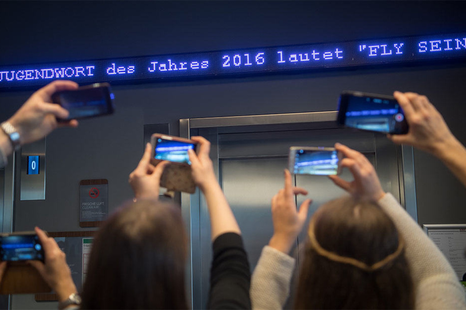 Die Worte "Fly sein" flimmern in München als "Jugendwort des Jahres" über den digitalen Newsticker eines Hotels.