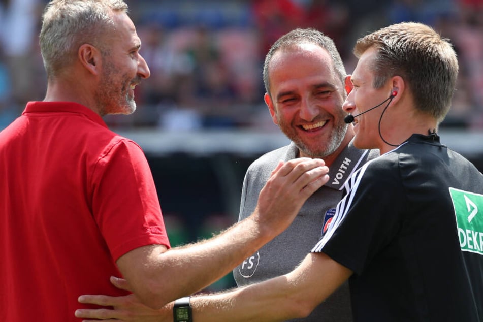 Der Heidenheimer Trainer Frank Schmidt (M) unterhält sich mit dem Stuttgarter Trainer Tim Walter (l) und dem Schiedsrichter Benjamin Cortus vor Spielbeginn.