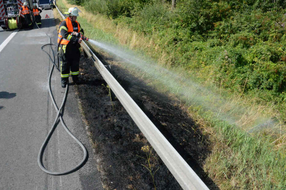 Ein Feuerwehrmann löscht das in Brand geratene Gras