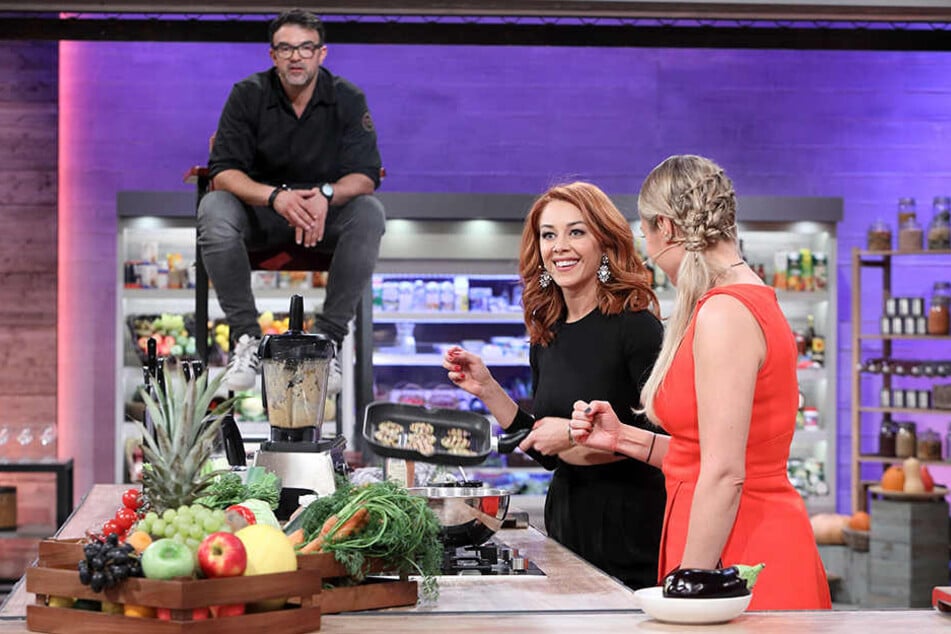 Beim Kochen bekommt Oana (Mitte) seelische Unterstützung von Profi-Koch und Coach Tarik Rose (links) und Moderatorin Ruth Moschner (rechts).
