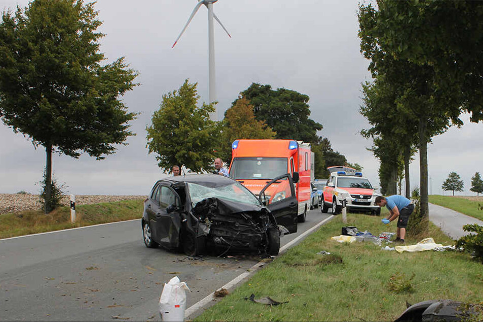 Mitten auf der Fahrbahn steht der demolierte Toyota. Drumherum liegen Unfalltrümmer.