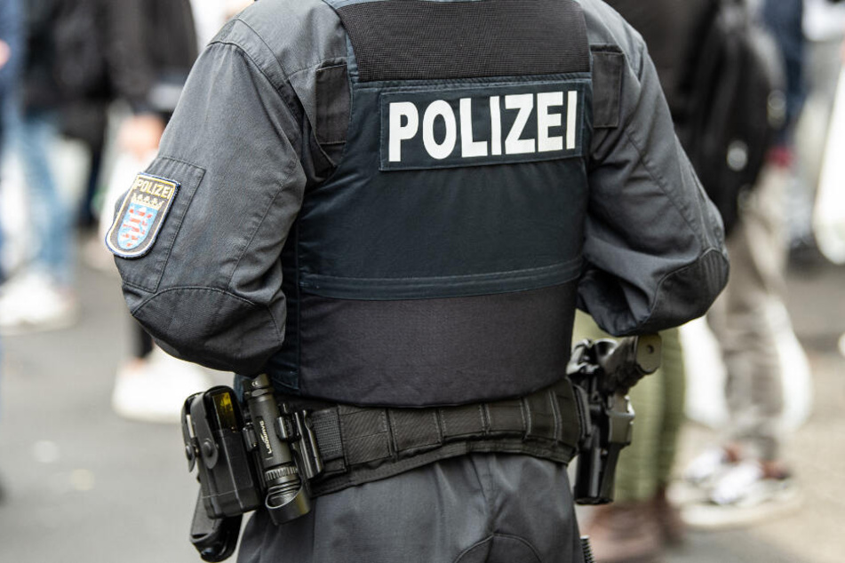 Ein Polizist steht bei einer Razzia im Kasseler Problemviertel um Platz "Am Stern" vor Passanten.