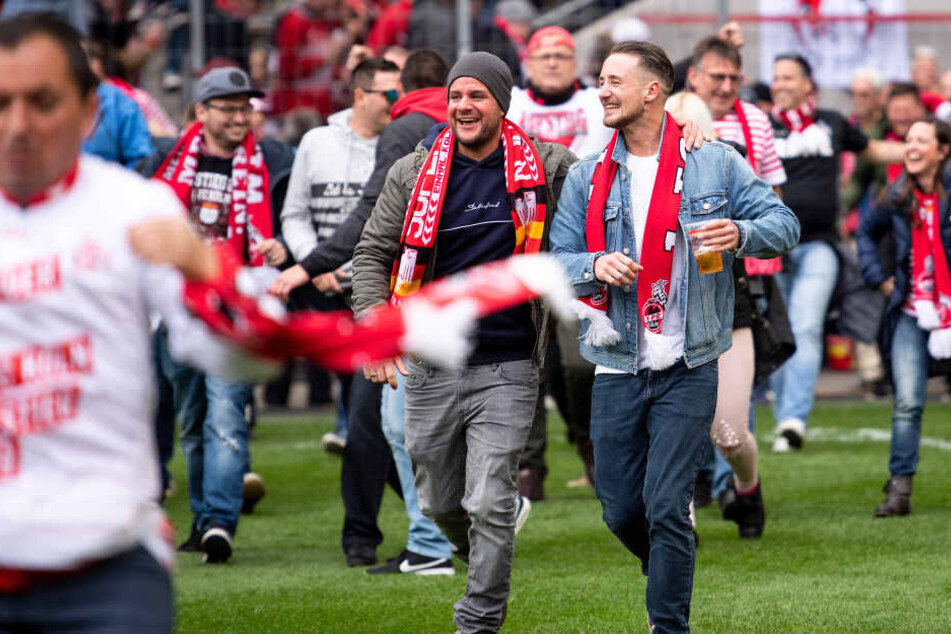 Kölner Fans stürmen den Platz und feiern den Aufstieg ihrer Mannschaft.