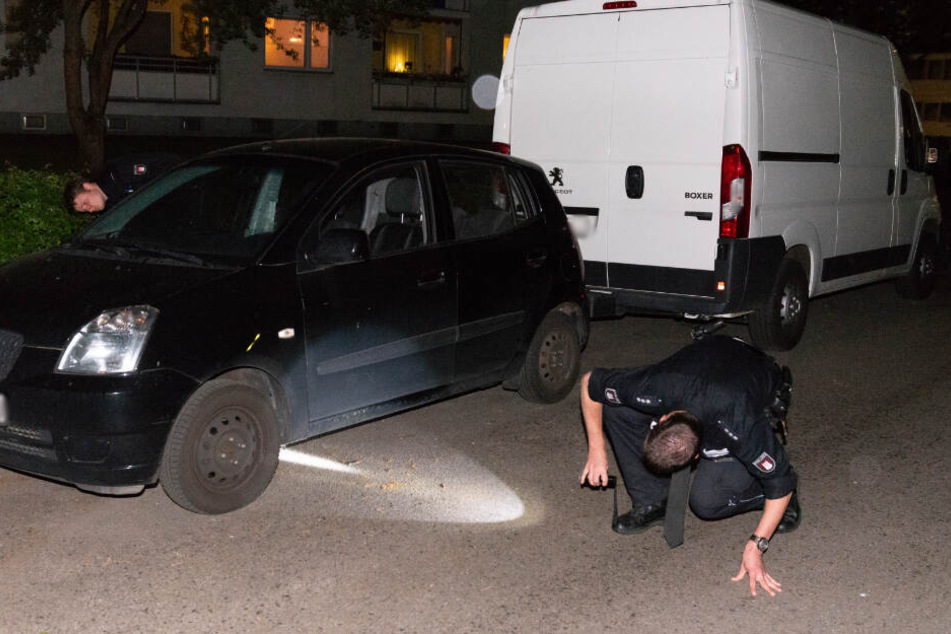Ein Polizeibeamter sucht mit einer Taschenlampe am Tatort nach Spuren.
