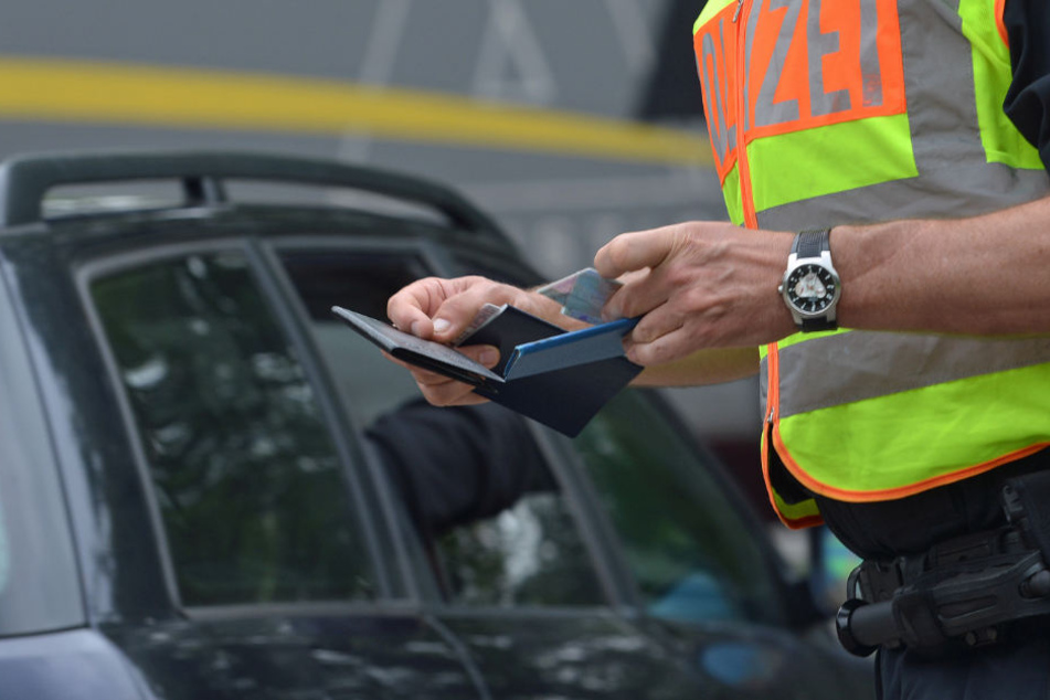 Ein Beamter kontrolliert die Papiere eines Autofahrers. (Symbolbild)