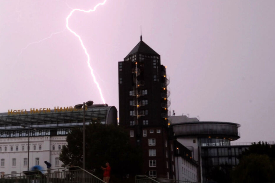 Ein Blitz zuckt bei den Landungsbrücken über den Hamburger Himmel. (Archivbild)