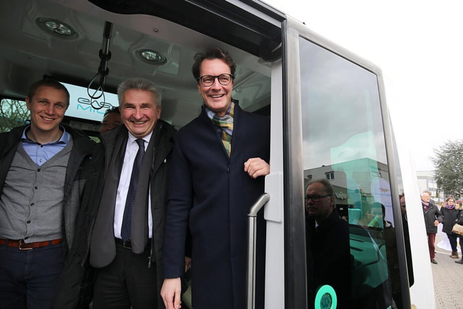NRW-Wissenschaftsminister Andreas Pinkwart (m) und VerkehrsministerHendrik Wüst (r) stehen neben monheims Bürgermeister Daniel Zimmermann in einem autonom fahrenden Bus.