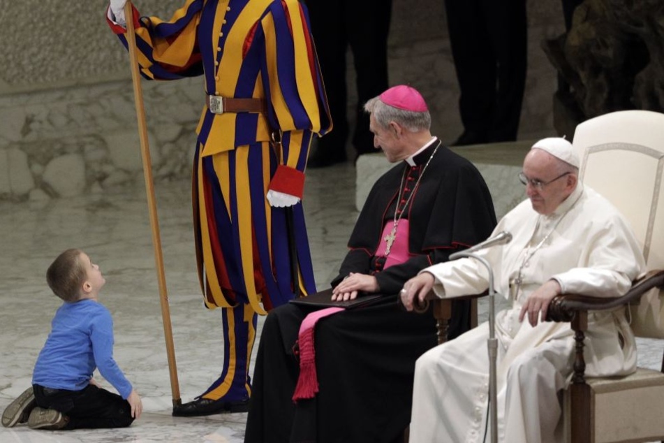 Papst Franziskus (r) und Erzbischof George Gaenswein (2.v.r.) lachen während ein Kind neben ihnen mit einem Mitglied der päpstlichen Schweizergarde spielen möchte.