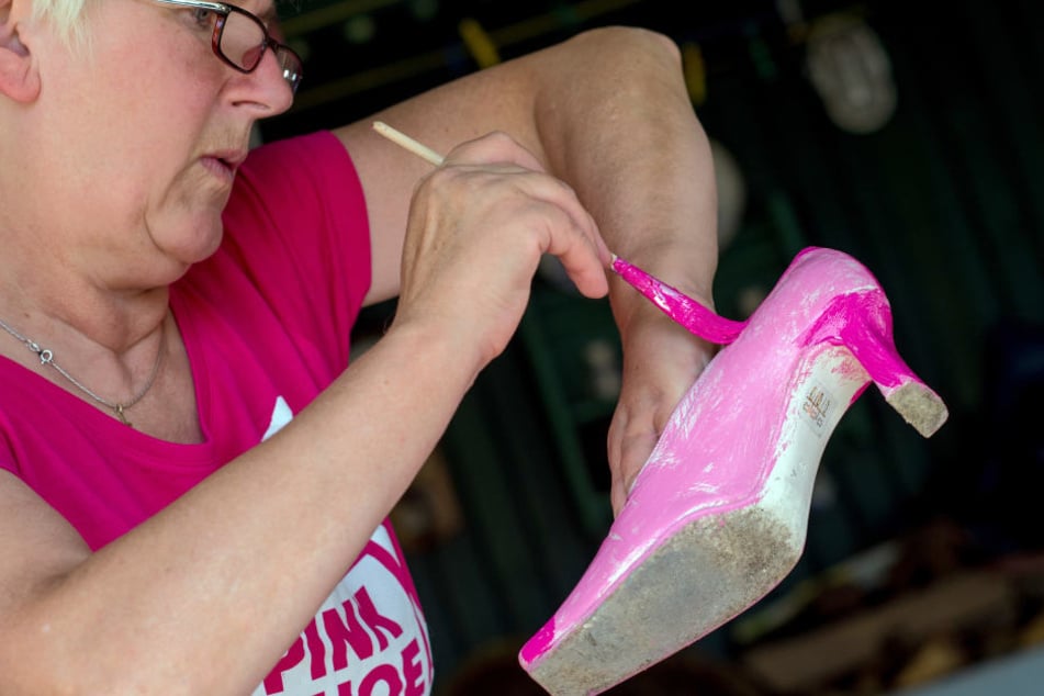 Doris Bastian vom Verein "Frauenselbsthilfe nach Krebs" kümmert sich mit einem Pinsel und viel pinker Farbe um einen High Heel.