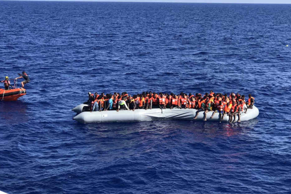 Flüchtlinge mit orangen Rettungswesten auf einem Schlauchboot - als Symbol der Solidarität werden bei der Seebrückenaktion am Samstag orange Papierschiffe gebastelt.