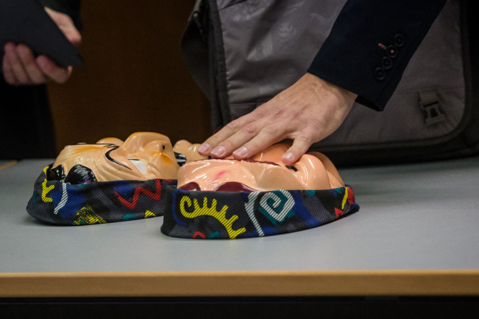 Ein Angeklagter legt zwei Hexenmasken im Amtsgericht Heilbronn auf den Tisch.