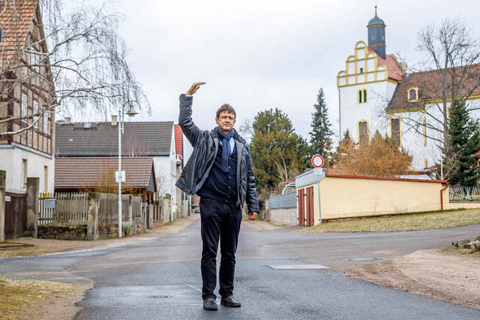 Der Coswiger Ordnungsamtsleiter Olaf Lier (56) vor Ort in Brockwitz: Die Häuser auf der tieferen Dorfseite (links) müssten angehoben werden, die Gebäude oberhalb der Kirche (rechts) liegen bereits hoch genug und flutsicher.