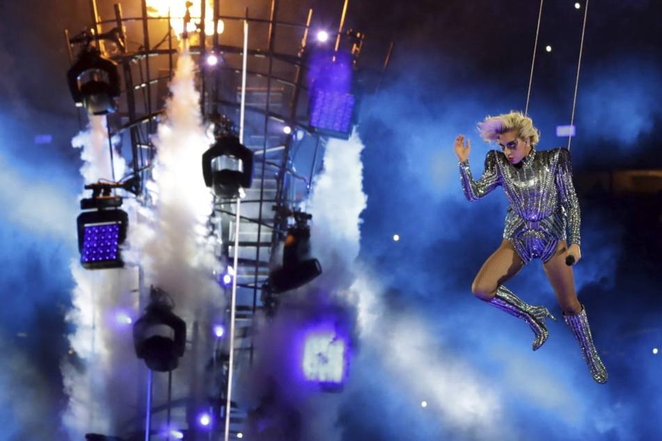 Nach einem patriotischen Appell geht es gleich weider mit der typischen Gaga-Show. Hier lässt sie sich vom Dach auf einen brennenden Turm abseilen.