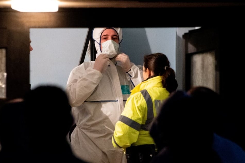 Ein Beamter der Spurensicherung steht im Flur eines Mehrfamilienhauses neben einer Polizistin.