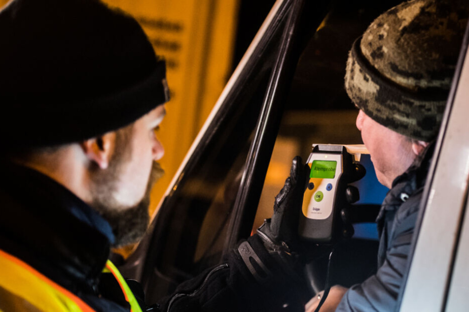 Ein Polizist führt bei einem Lkw-Fahrer eine Alkoholkontrolle durch.