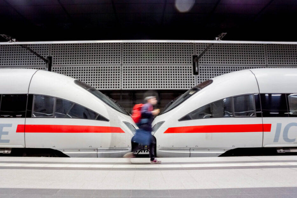 Ein Mann geht im Berliner Hauptbahnhof an einem ICE entlang.
