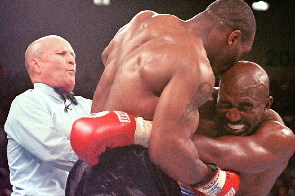 Der Weltmeister im Schwergewicht, Evander Holyfield (r), verzieht am 28.06.1997 in Las Vegas das Gesicht, nachdem ihn sein Herausforderer Mike Tyson (M) ins Ohr gebissen hat. Der Ringrichter Lane Mills (l) unterbricht in diesem Moment den Kampf.