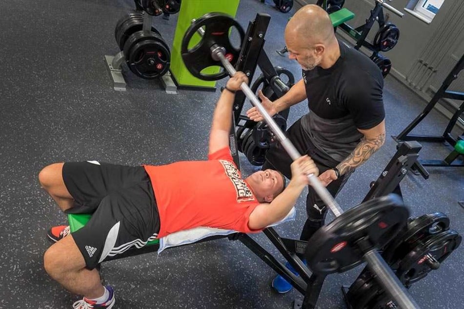 Mit Vorsätzen Gewichte stemmen: Robert Maintok (30) mit Trainer Vadim Istomin (46) beim Bankdrücken im Studio Fit/One.