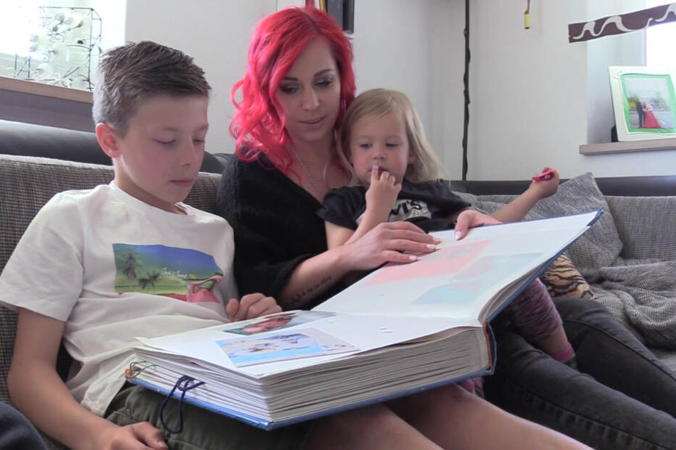 Nico schaut mit seiner Mutter Nadine Kilger und seiner Schwester ein Fotoalbum an.
