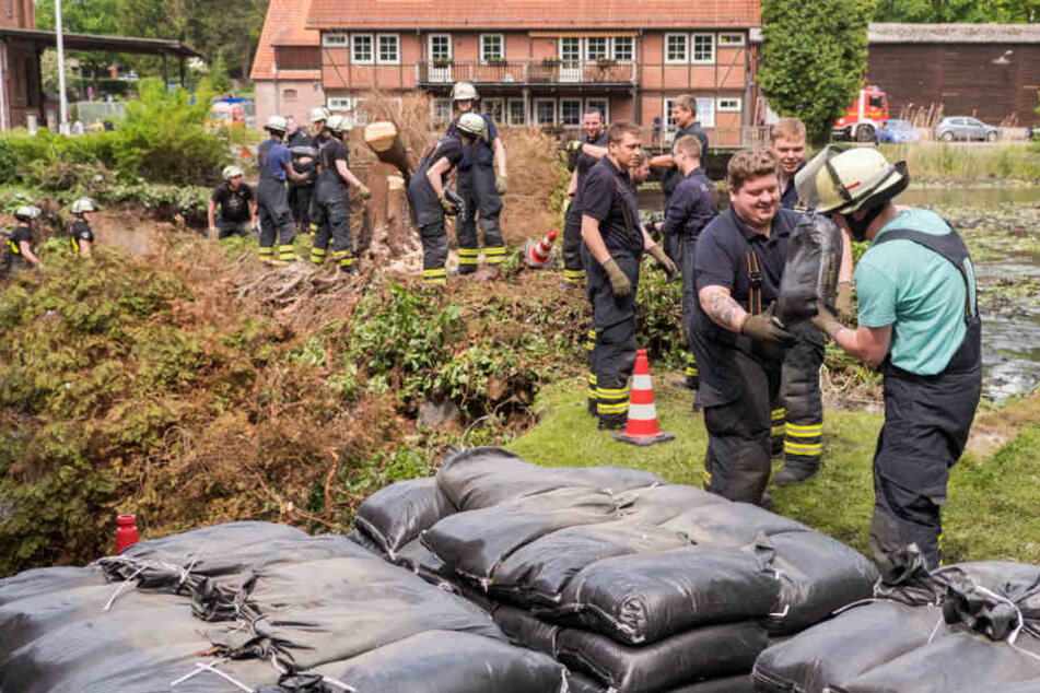 Auch einen Tag nach dem Unwetter verlegen Feuerwehrleute in Kirchsteinbeck tausende Sandsäcke.