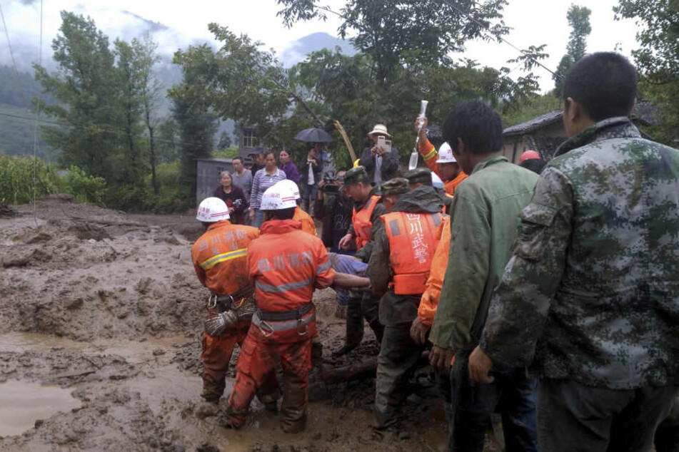 Rettungskräfte tragen am 08.08.2017 in Gengdi (China) einen Mann, der bei einem Erdrutsch verletzt wurde. Durch schwere Regenfälle war der Erdrutsch ausgelöst worden, der möglicherweise mehr als 20 Menschen das Leben kostete.