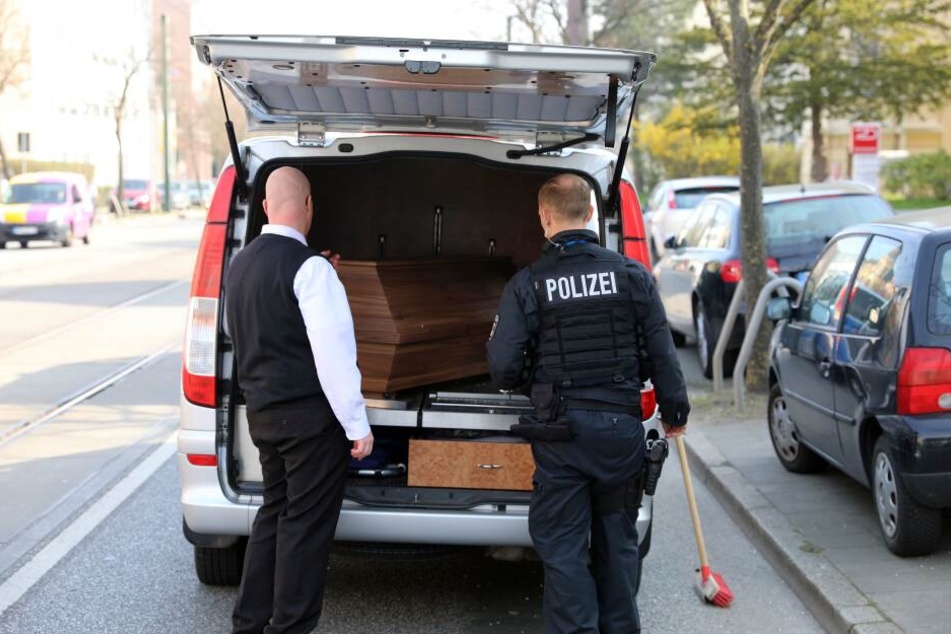 Der Bestatter und ein Polizeibeamter überprüfen den Sarg im Unfallwagen.