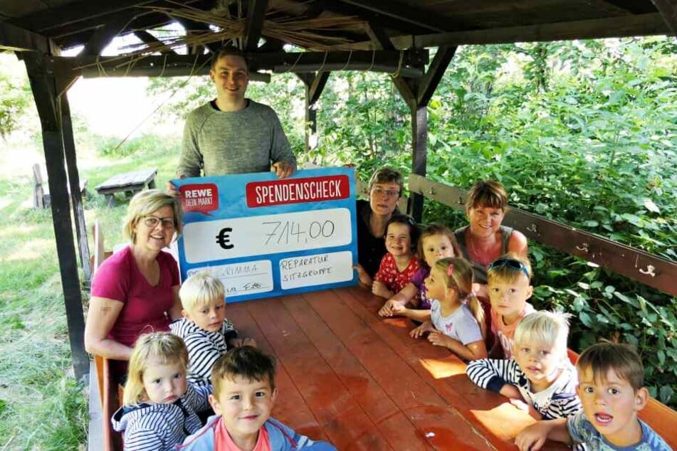 Rewe-Marktleiter Florian Schill mit den Kindern der Kita "Pusteblume" in ihrem wieder aufgebauten Waldidyll.