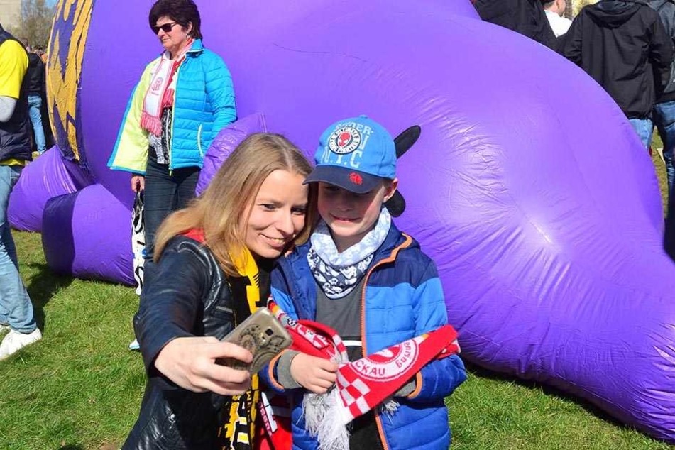 Fans posierten für Erinnerungsfotos vorm lila Aue-Schwein.