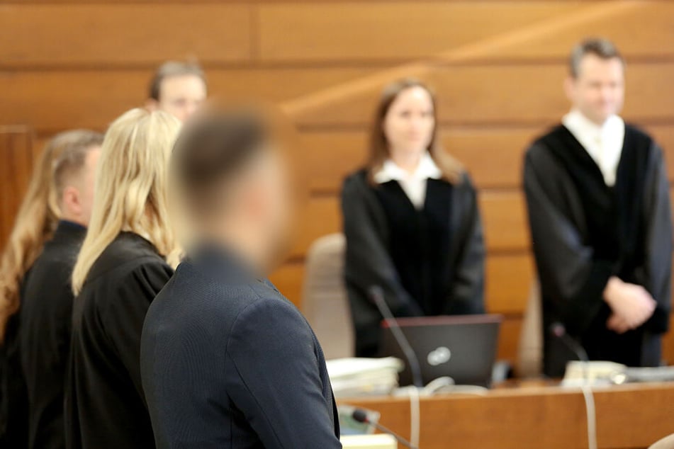Die beiden angeklagten Journalisten (l) und ihre Anwälte stehen im Saal des Landgerichts, während die Richter auf ihren Plätzen stehen.