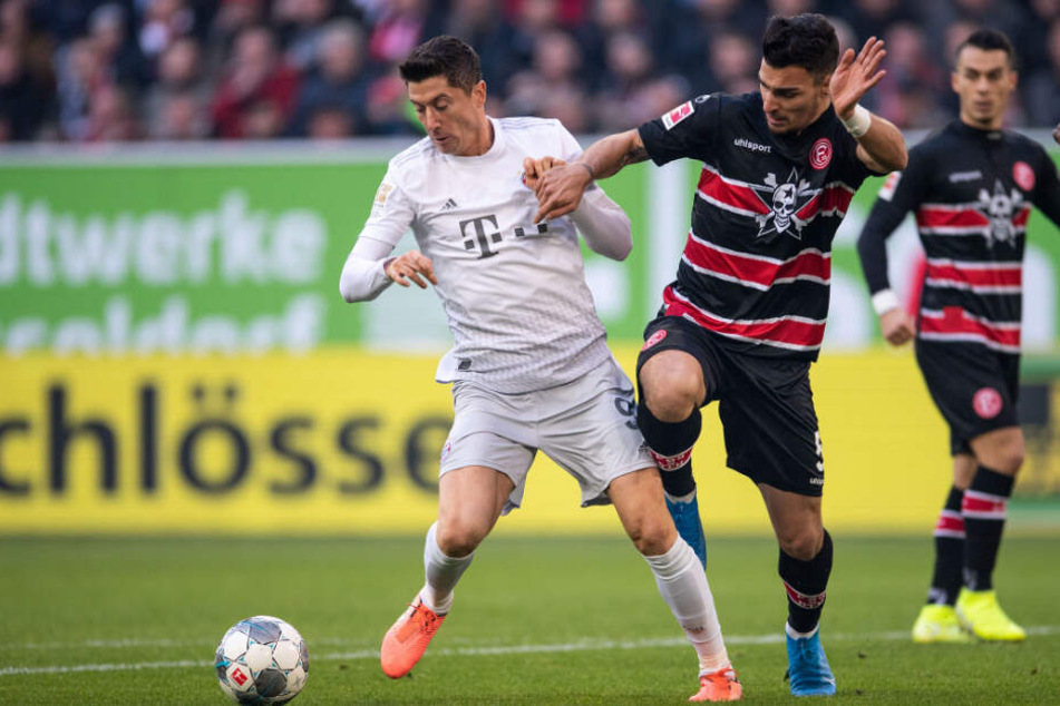 Robert Lewandowski (l) vom FC Bayern und Düsseldorfs Kaah Ayhan kämpfen um den Ball.
