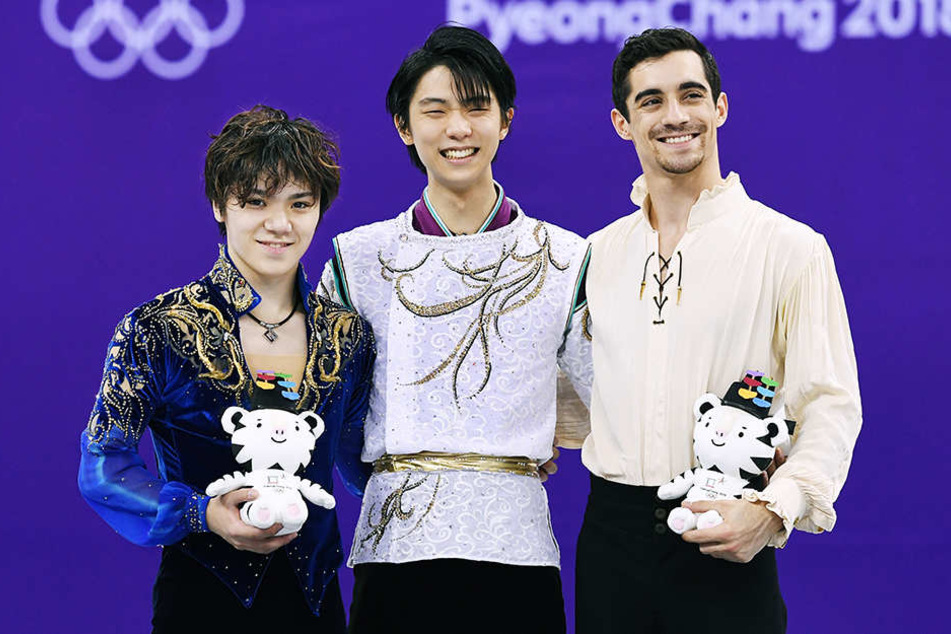 Olympiasieger Yuzuru Hanyu (M), der Zweitplazierte Shoma Uno (l), beide aus Japan und der Dritte, Javier Fernandez aus Spanien, lächeln bei der Siegerehrung.