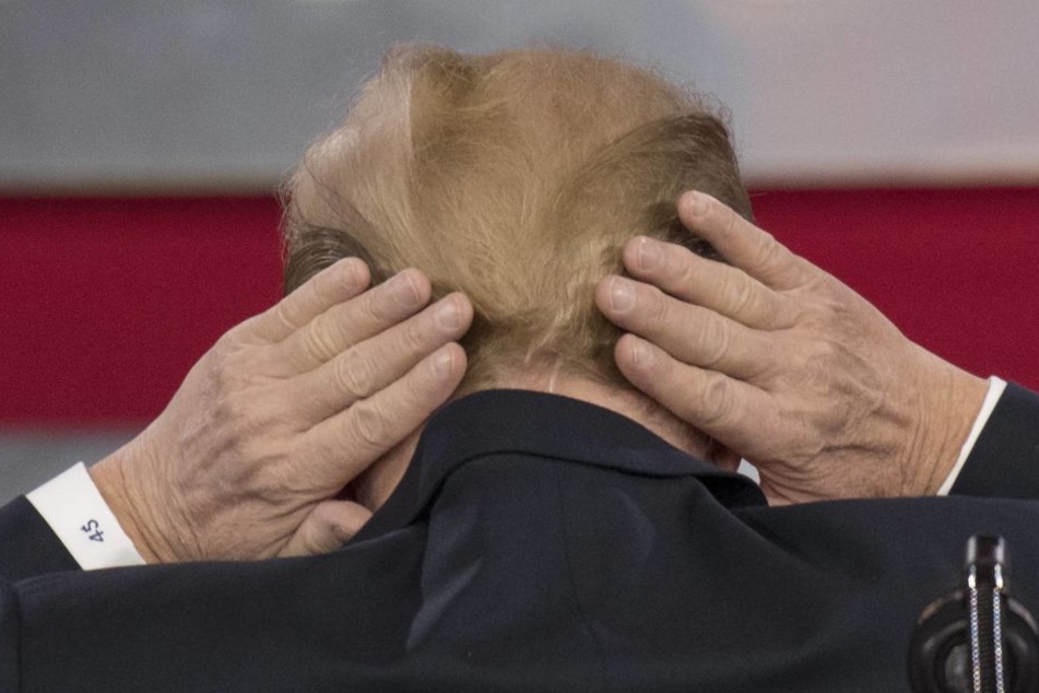 Donald Trump versucht seine kahle Stelle am Hinterkopf zu verstecken.