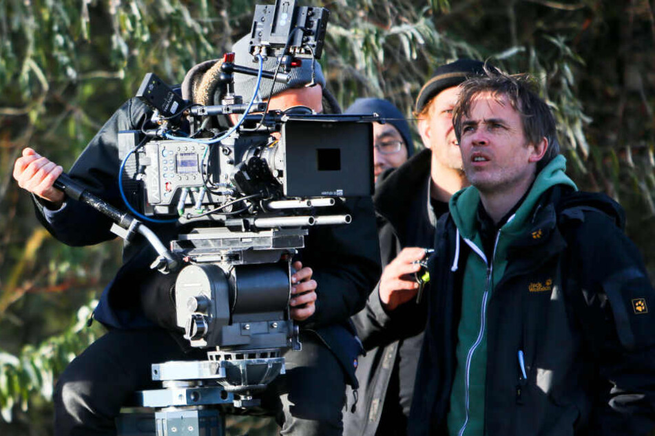 Regisseur Eoin Moore (rechts) blickt bei TV-Dreharbeiten für "Polizeiruf 110" am Strand von Markgrafenheide (Mecklenburg-Vorpommern) auf den Monitor der Filmkamera.