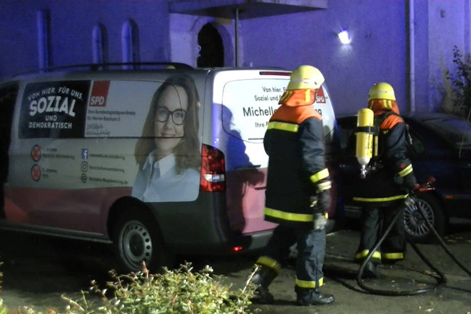 Feuerwehrleute stehen neben dem Lieferwagen, der Opfer des Brandanschlags wurde.