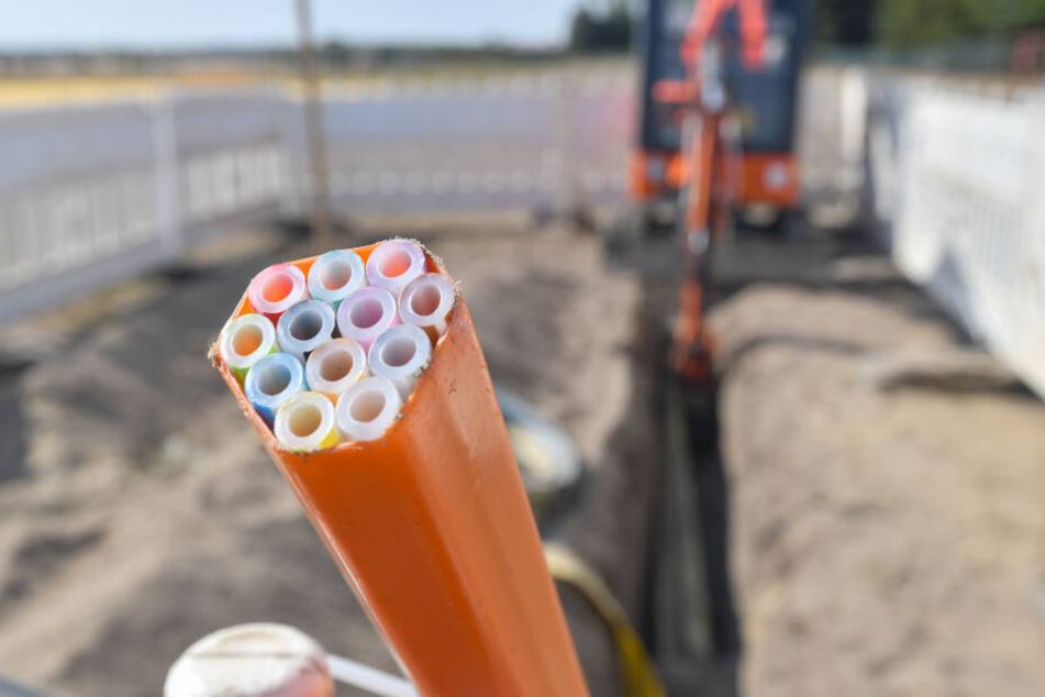 arbige Leerrohre, in die später die Glasfaserkabel verlegt werden, ragen aus einem Graben auf einer Baustelle in Brandenburg.