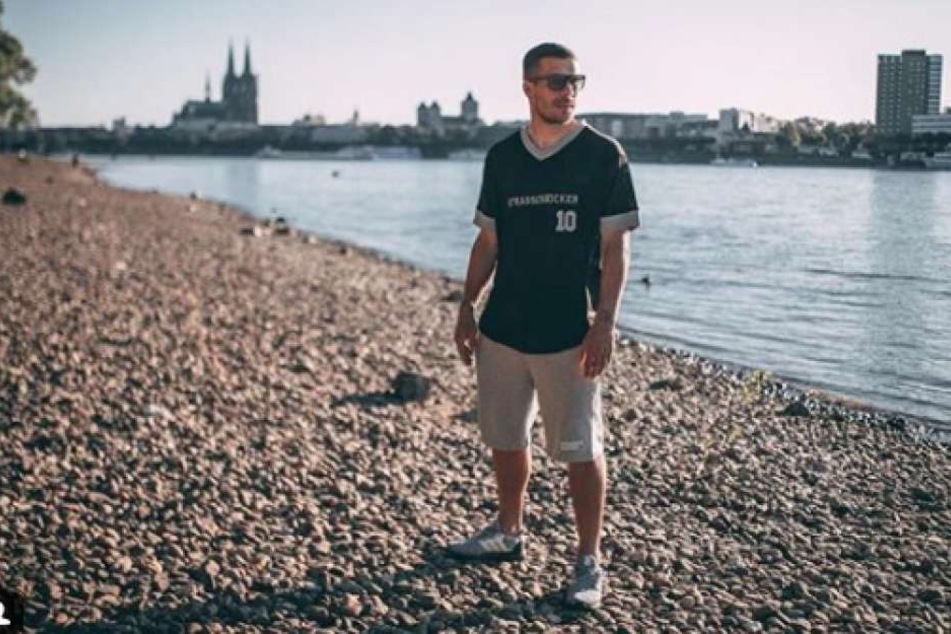 Hier steht Lukas Podolski am Rhein in Köln.