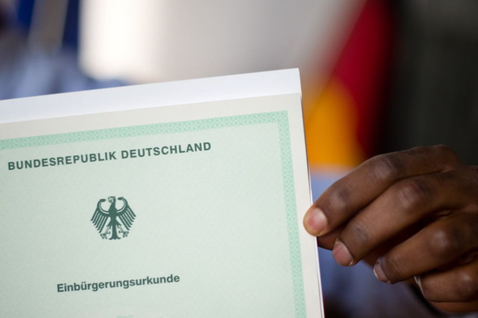 Ein Mann aus Afrika zeigt bei einer Einbürgerungsfeier stolz seine Einbürgerungsurkunde.