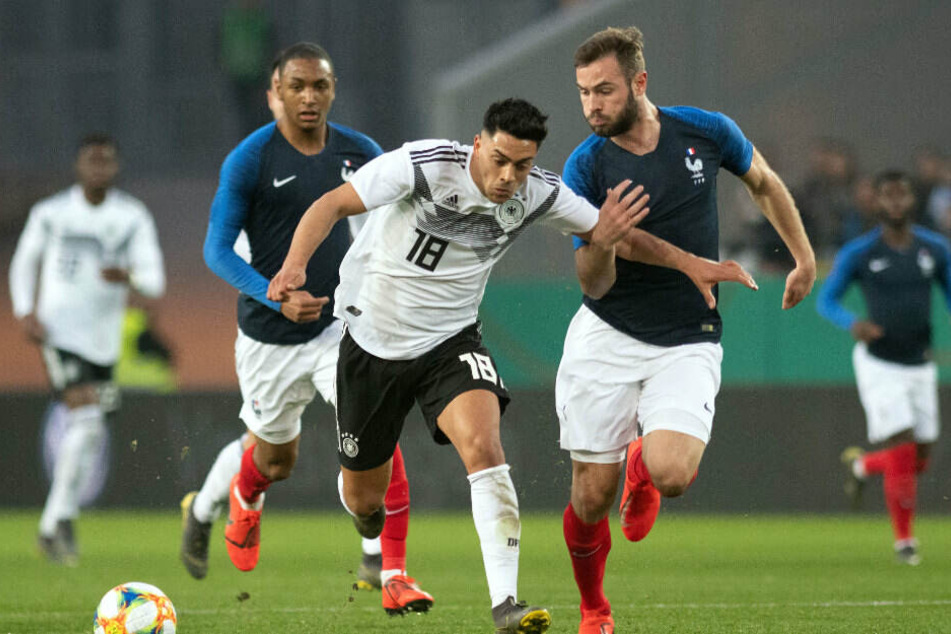 Deutschlands Nadiem Amiri (M) und Lucas Tousart (r) von Frankreich kämpfen um den Ball.