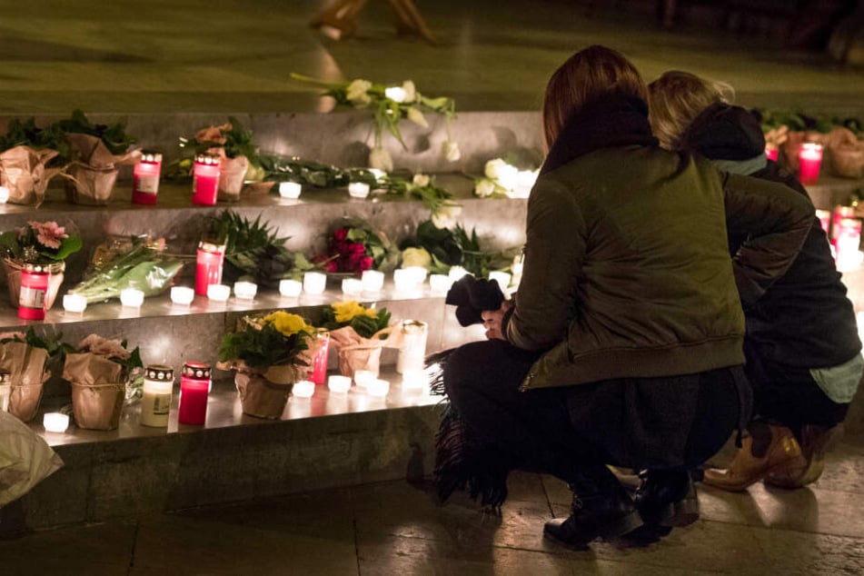 Zwei junge Frauen legen Blumen und Kerzen bei der Gedenkfeier für die getötete Mireille ab.