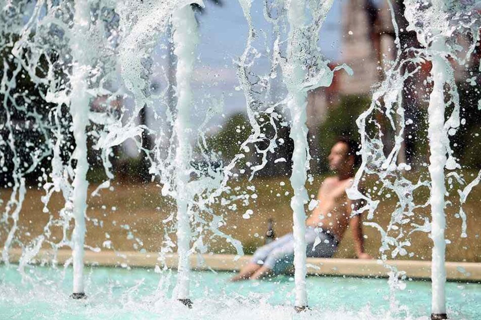 Ein Leipziger genießt ein kühles Fußbad in den Brunnen am Marktplatz.