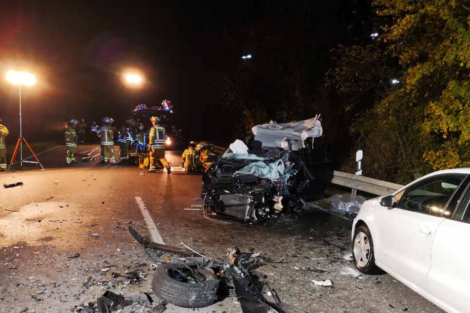 Trümmerteile liegen vor dem völlig zerstörten Auto.