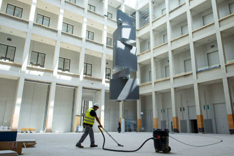 Ein Arbeiter saugt den noch abgedeckten Boden des Humboldt-Forums im neuen Berliner Stadtschloss.