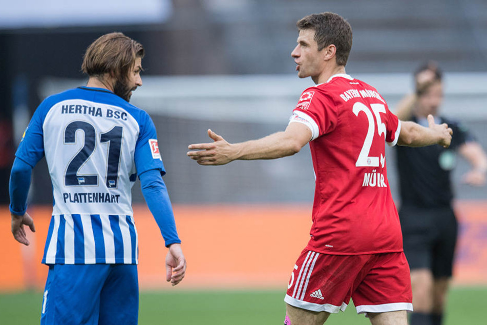 Bayerns Thomas Müller (r) steht mit einer ratlosen Geste auf dem Spielfeld und blickt zu Berlins Marvin Plattenhardt.