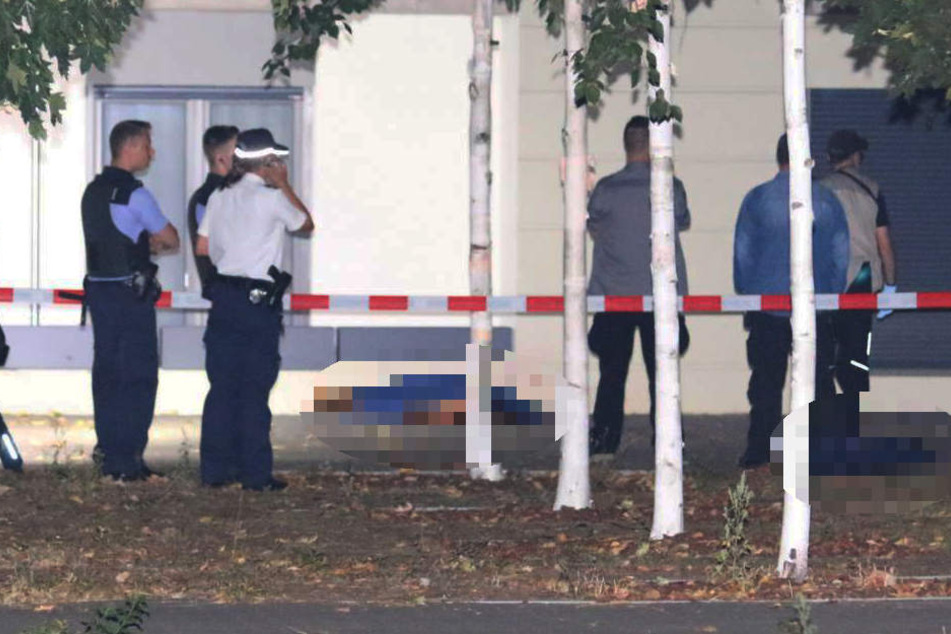 Die Polizei sichert den Bereich und deckt die toten Körper ab.
