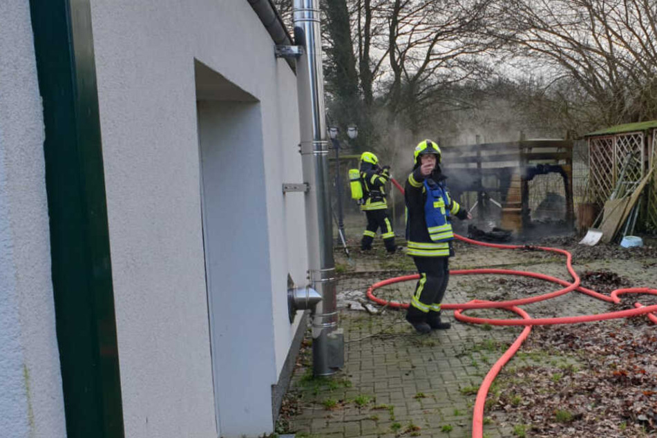 Feuerwehrleute löschen die brennende Hundehütte.